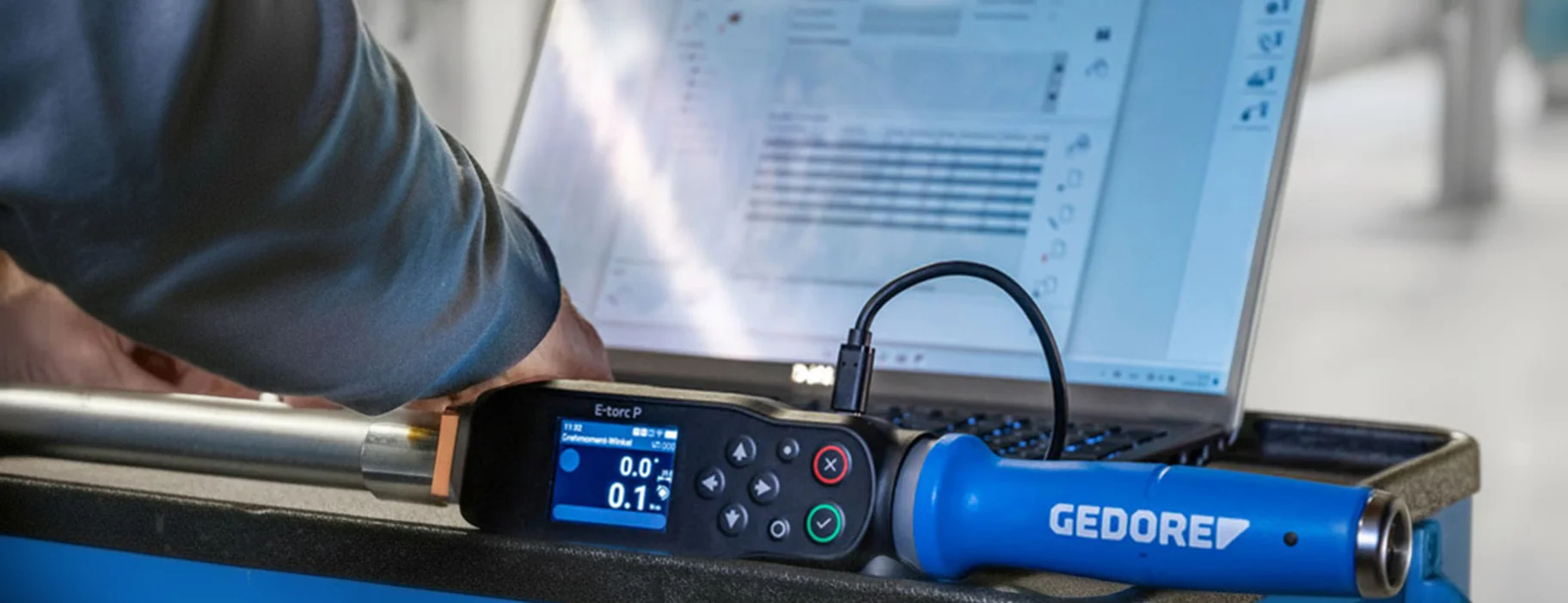 Elektronischer Drehmomentschlüssel von GEDORE auf einem Werkstattwagen vor einem Laptop