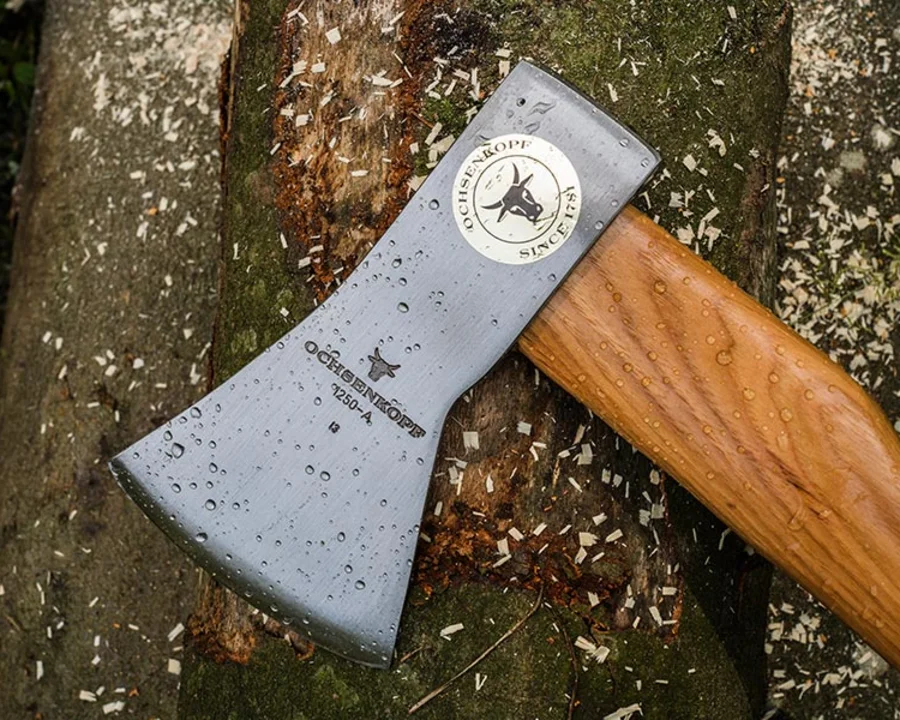 OCHSENKOPF Axt mit traditionellem Holzstiel liegt auf einem Baumstamm im Wald