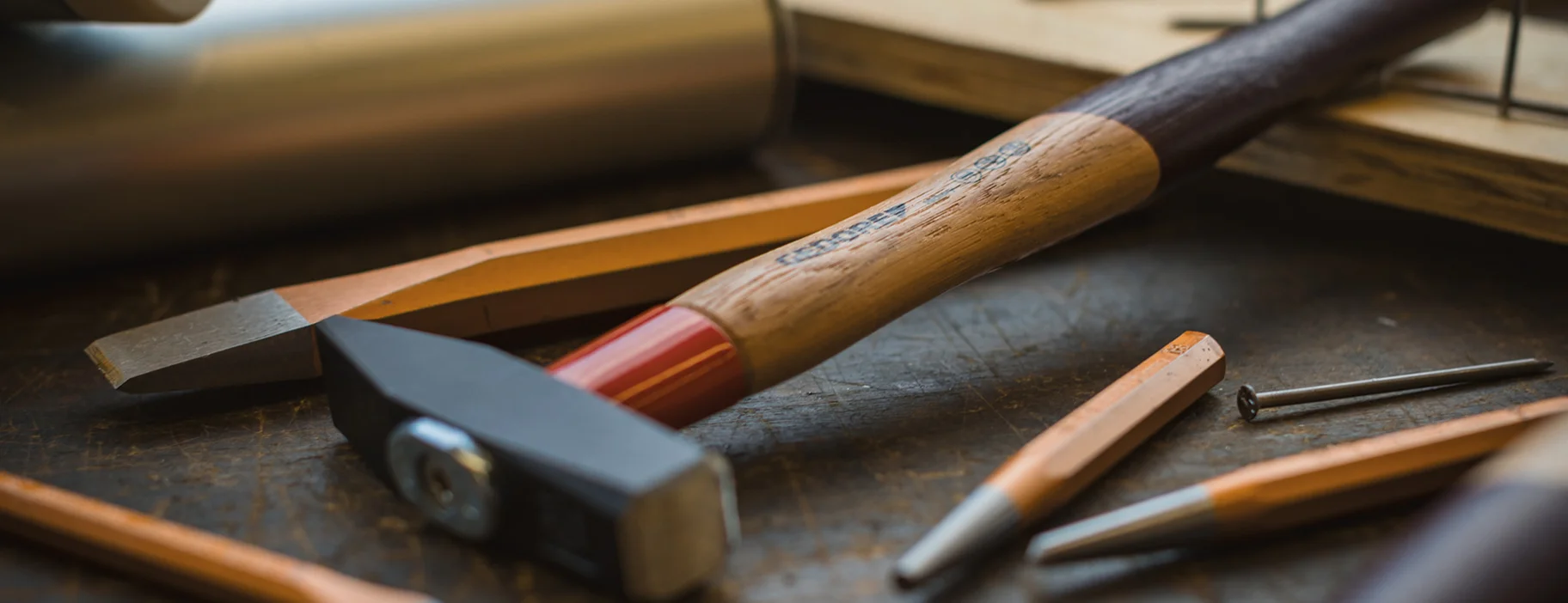 GEDORE Hammer mit Rotband-Plus auf einer Arbeitsfläche neben unterschiedlichen Schlagwerkzeugen